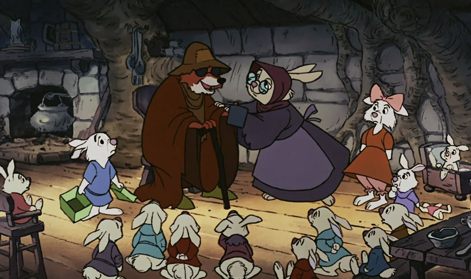 Un renard animé, vêtu d'une cape brune, rappelant Robin des Bois, discute avec un lapin vêtu d'une robe violette, entouré de plusieurs lapins, dans une salle rustique aux murs de pierre. Revivez la magie de sa première, le 8 novembre 1973.