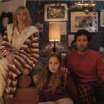 Une femme, un homme et une jeune fille sont assis sur le canapé d'un salon, l'air surpris. La pièce est décorée d'œuvres d'art et de couronnes de Noël pour Le Plus Beau Des Noëls, inspiré de la magie du Court-métrage Noël Disney.