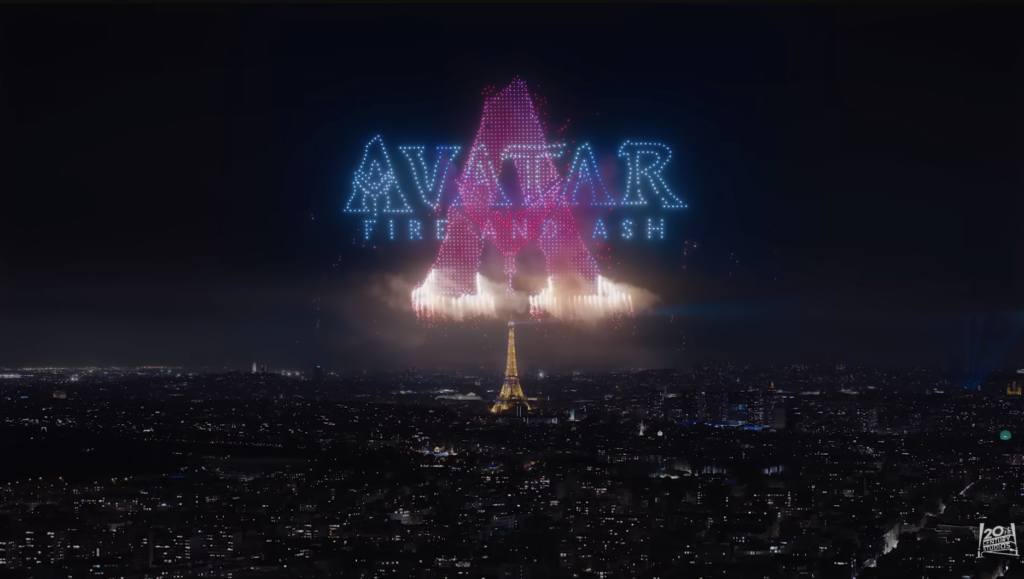 La Tour Eiffel de nuit sous un feu d'artifice et des drones Avatar forme le texte "AVATAR : THE LAST AIRBENDER" et une grande lettre "A" en lumières bleues et roses, évoquant la magie du Parc Walt Disney Studios.