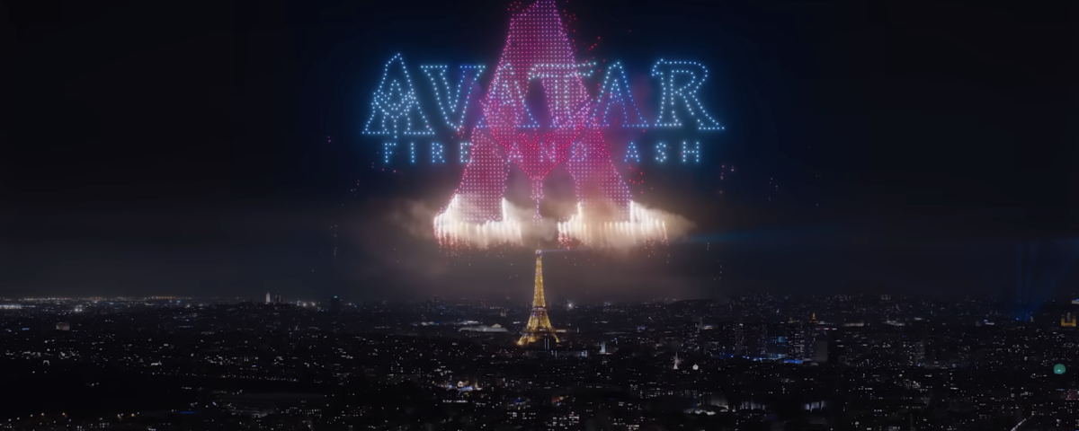 La Tour Eiffel de nuit sous un feu d'artifice et des drones Avatar forme le texte "AVATAR : THE LAST AIRBENDER" et une grande lettre "A" en lumières bleues et roses, évoquant la magie du Parc Walt Disney Studios.