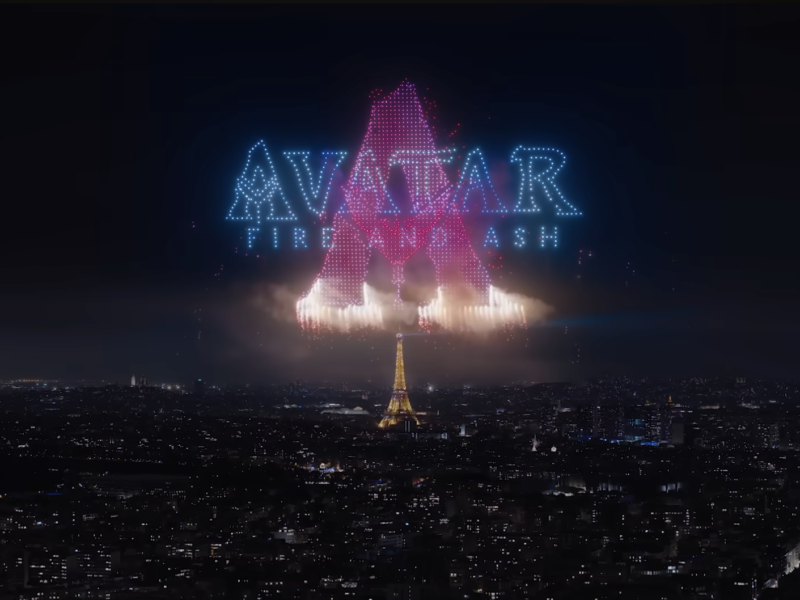 La Tour Eiffel de nuit sous un feu d'artifice et des drones Avatar forme le texte "AVATAR : THE LAST AIRBENDER" et une grande lettre "A" en lumières bleues et roses, évoquant la magie du Parc Walt Disney Studios.