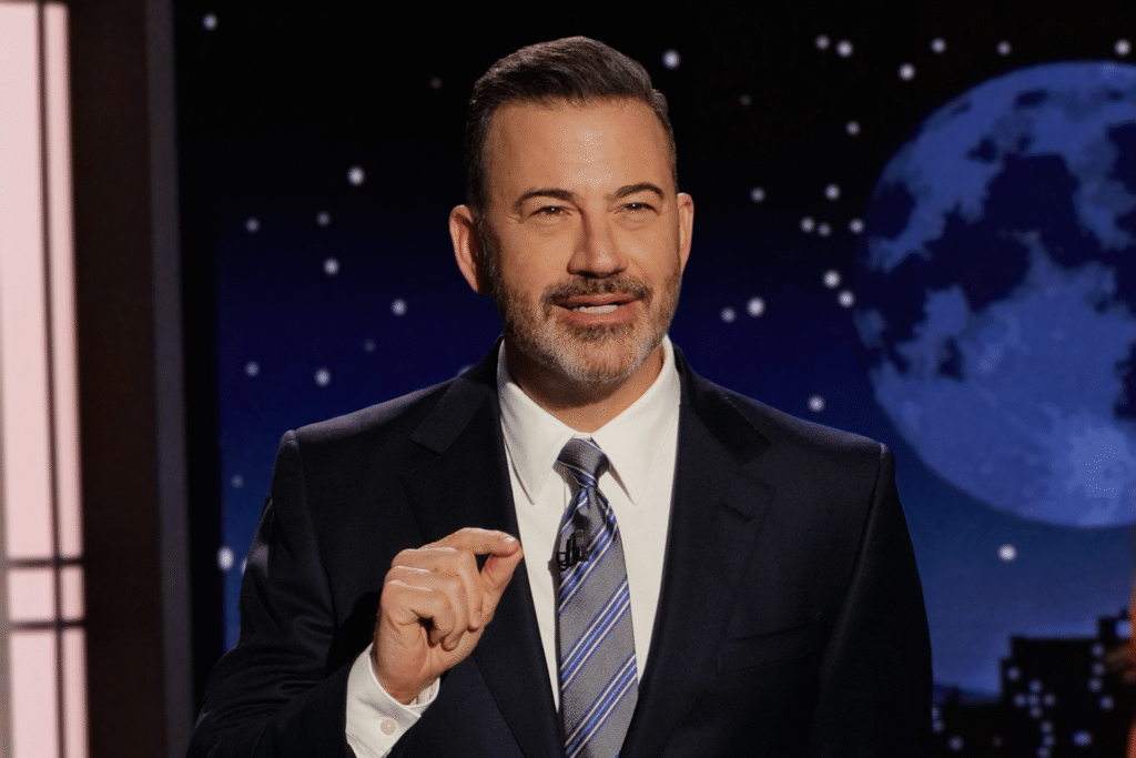 Un homme en costume-cravate parle sur scène la nuit, avec une grande image de la lune en arrière-plan, lors d'un épisode de Jimmy Kimmel Live sur ABC.