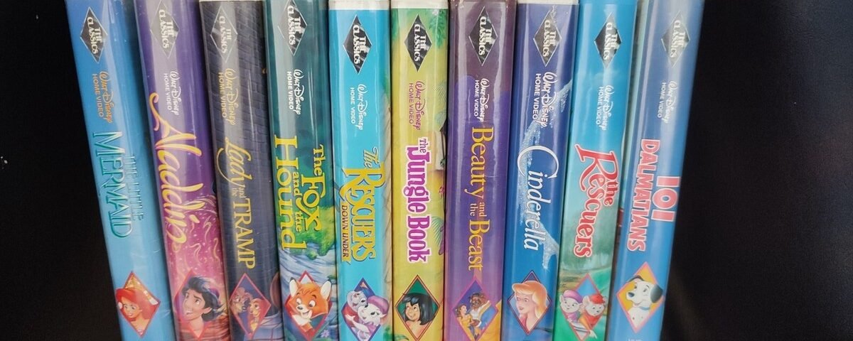 Une collection de onze cassettes Disney Black Diamond VHS, dont La Belle et la Bête, La Petite Sirène, Aladdin et bien d'autres encore, toutes des VHS rares et précieuses, disposées côte à côte sur une étagère noire.