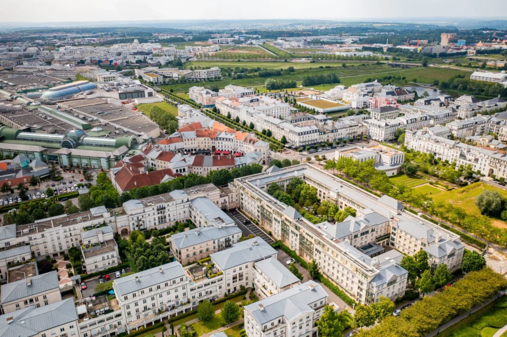 Vue aérienne de Val d'Europe montrant des maisons blanches, des espaces verts luxuriants, des routes bien planifiées et des entreprises éloignées.