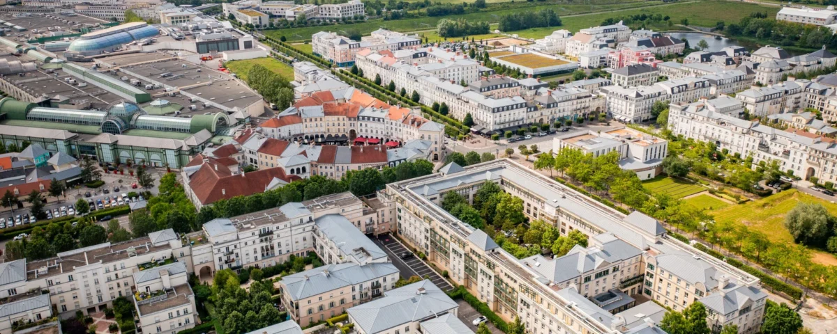 Vue aérienne de Val d'Europe montrant des maisons blanches, des espaces verts luxuriants, des routes bien planifiées et des entreprises éloignées.
