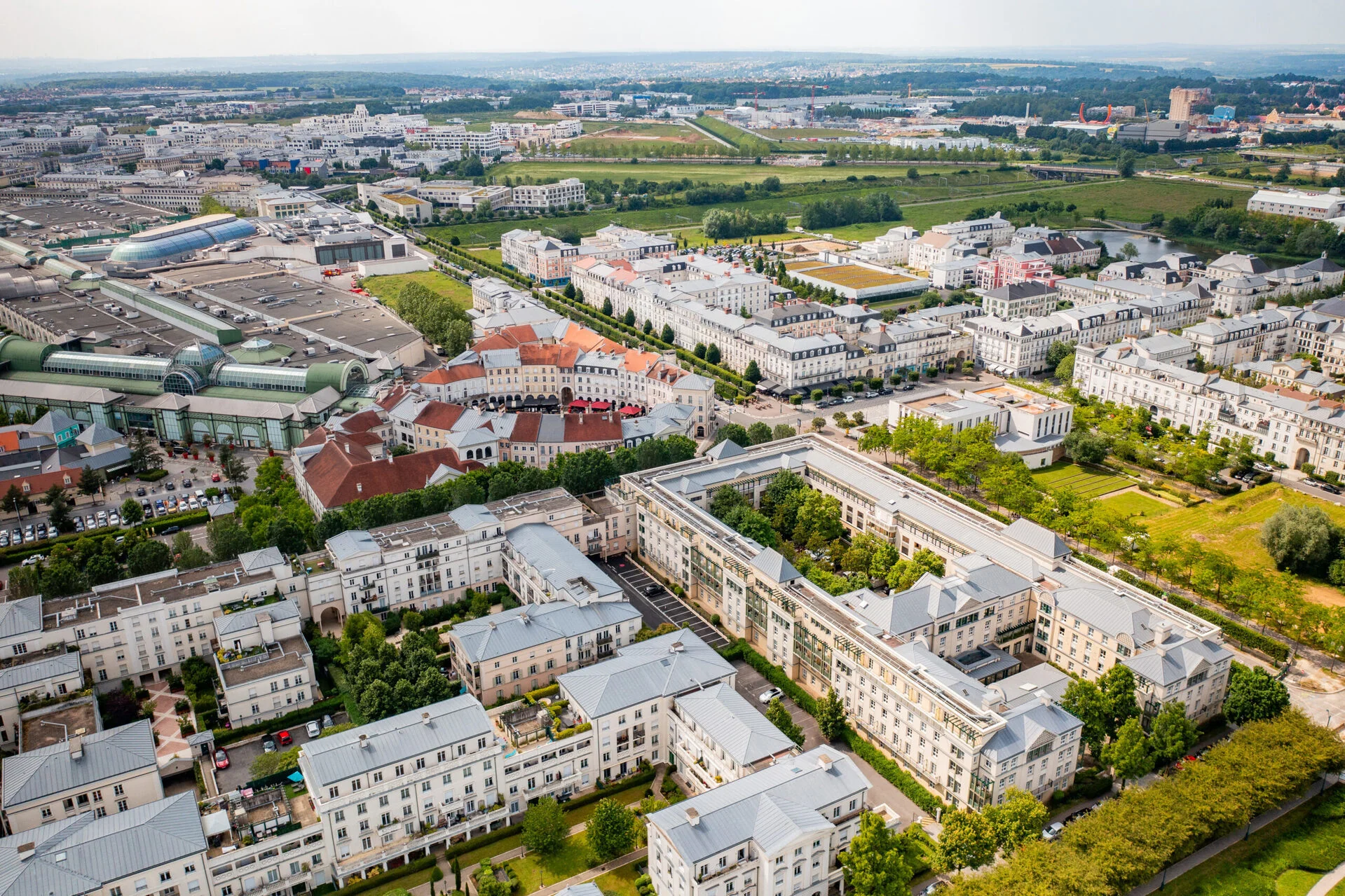 Vue aérienne de Val d'Europe montrant des maisons blanches, des espaces verts luxuriants, des routes bien planifiées et des entreprises éloignées.