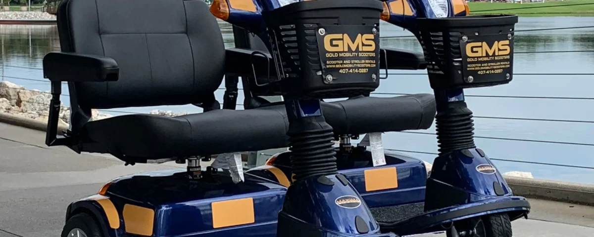 Deux scooters électriques de location bleus et orange portant l'inscription GMS sont garés côte à côte sur une allée pavée près d'un plan d'eau à Chalifert, non loin de Disneyland Paris.