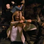 Une femme, qui rappelle Buffy, brandit un pieu en bois et combat des personnages monstrueux dans un environnement sombre et chaotique qui rappelle Sunnydale.