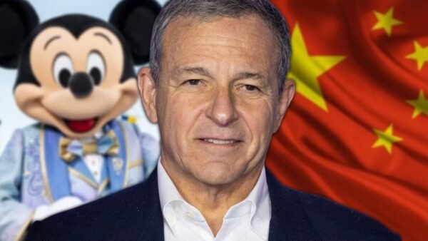 Un homme se tient devant un personnage de Mickey Mouse et un drapeau chinois, mettant en avant Disney en Chine et ses ambitions en matière d'investissement Disney.