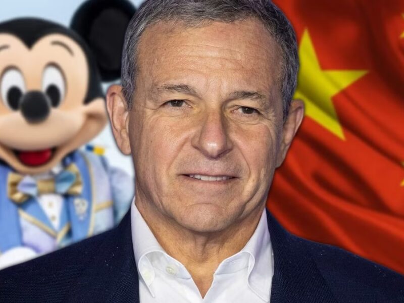 Un homme se tient devant un personnage de Mickey Mouse et un drapeau chinois, mettant en avant Disney en Chine et ses ambitions en matière d'investissement Disney.