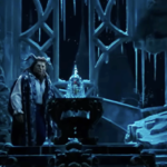 Un interprète costumé se tient à côté d'une rose en verre sur la scène, entouré de décors glacés de style gothique sous un éclairage bleu, évoquant la nostalgie des actions classiques en direct de Disney avec un approfondissement émotionnel.