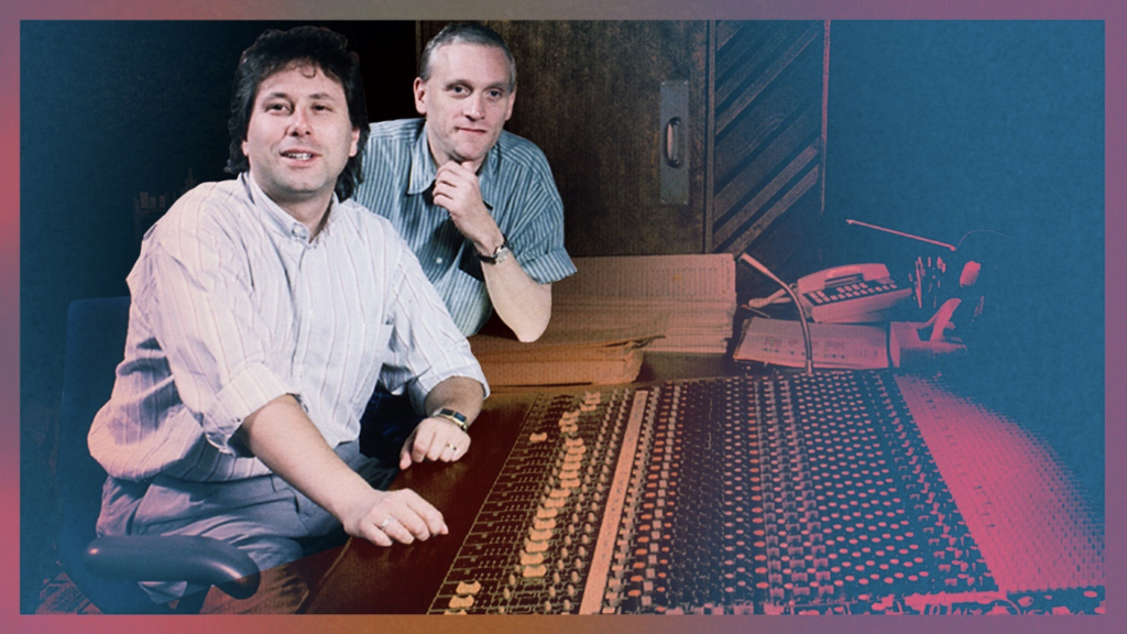 Deux hommes sont assis et debout derrière une grande console de mixage audio dans un studio d'enregistrement, entourés de pupitres et d'équipements, alors qu'un sentiment de nostalgie envahit l'air.