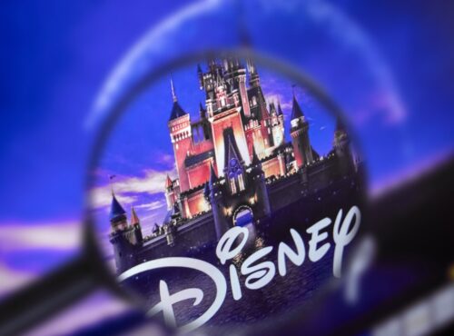 Une loupe se concentre sur le logo Disney avec un château en arrière-plan dans un ciel bleu et violet, soulignant la présence emblématique de Disney et ses obligations en 2020.
