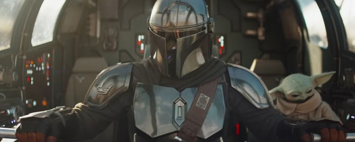 Un Mandalorien en armure métallique pilote un vaisseau spatial, avec Grogu, la petite créature verte, assis à proximité dans le cockpit.