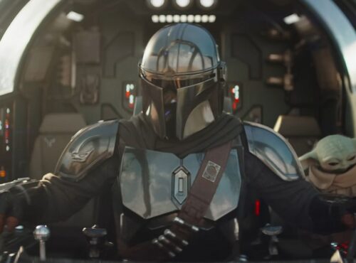 Un Mandalorien en armure métallique pilote un vaisseau spatial, avec Grogu, la petite créature verte, assis à proximité dans le cockpit.