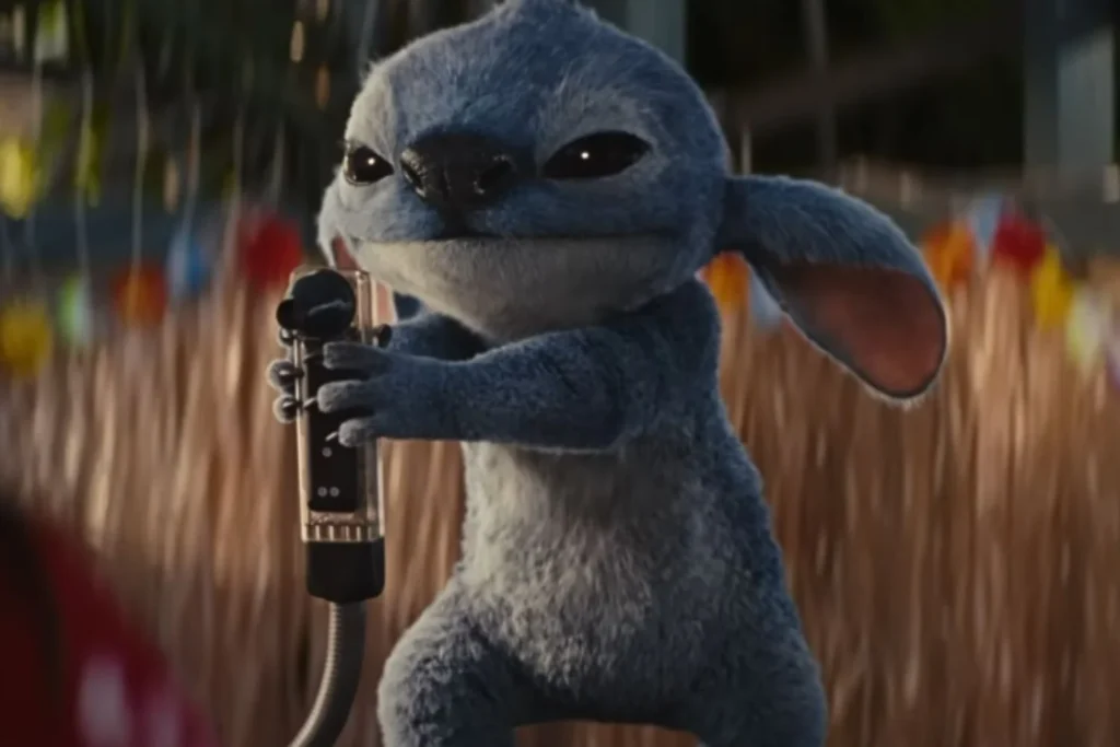 Une créature bleue animée avec de grandes oreilles, inspirée de Lilo & Stitch, tient un microphone tout en se tenant à l'extérieur.
