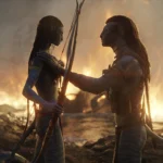 Deux personnages humanoïdes à la peau bleue d'Avatar Fire And Ash se font face avec des armes, du feu et de la fumée tourbillonnant en arrière-plan sur un paysage rocheux - une scène saisissante d'un film Disney qui a fait sensation au box-office mondial.