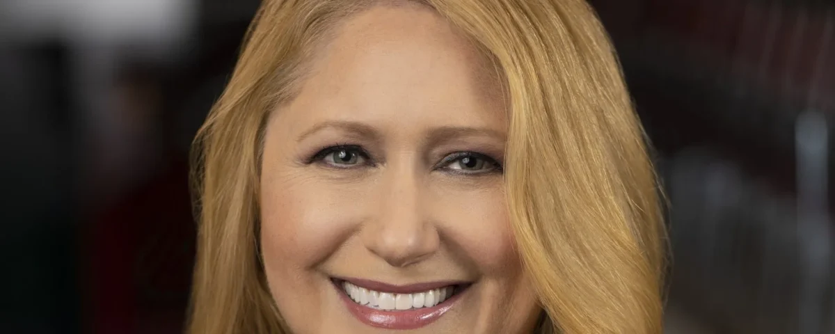 Une femme aux longs cheveux blonds sourit à l'appareil photo dans un portrait en gros plan, reflétant la chaleur et le charme que l'on retrouve souvent dans les émissions de Disney Entertainment Television.