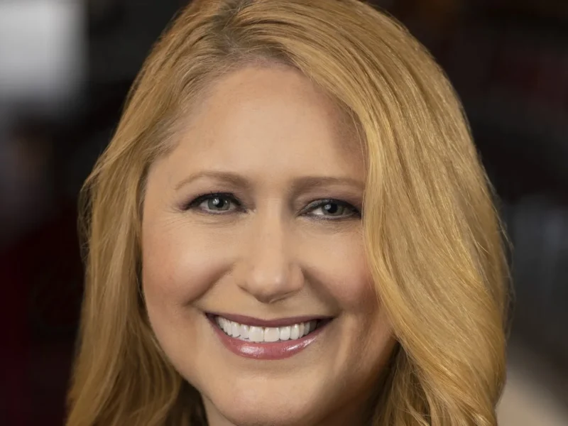 Une femme aux longs cheveux blonds sourit à l'appareil photo dans un portrait en gros plan, reflétant la chaleur et le charme que l'on retrouve souvent dans les émissions de Disney Entertainment Television.