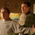 Deux hommes se tiennent dans une cuisine ; le plus jeune, qui ressemble à Malcolm (Frankie Muniz), parle avec emphase, les bras tendus, tandis que le plus âgé, qui ressemble beaucoup au personnage de Bryan Cranston, regarde la scène d'un air inquiet.