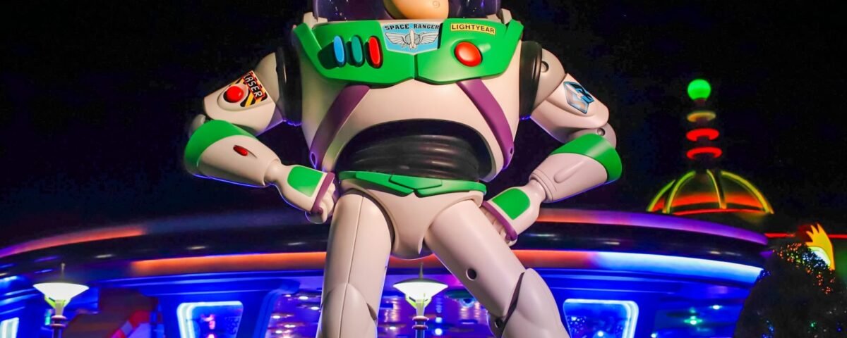 Une grande statue de Buzz l'Éclair se dresse devant le bâtiment futuriste de Space Mountain, illuminé de nuit, dans le parc d'attractions de Disney World.