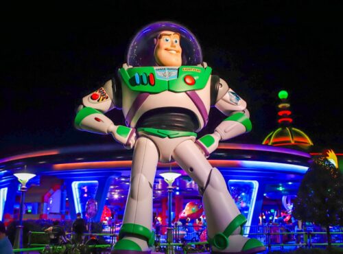 Une grande statue de Buzz l'Éclair se dresse devant le bâtiment futuriste de Space Mountain, illuminé de nuit, dans le parc d'attractions de Disney World.