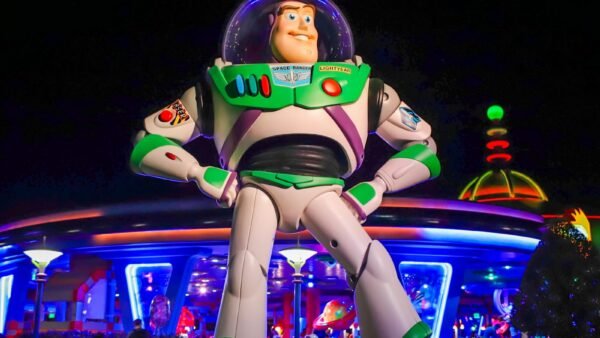 Une grande statue de Buzz l'Éclair se dresse devant le bâtiment futuriste de Space Mountain, illuminé de nuit, dans le parc d'attractions de Disney World.