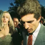 Une femme et un homme en tenue de soirée marchent à l'extérieur dans une foule, avec des arbres et un ciel dégagé en arrière-plan, évoquant l'élégance d'une scène de Love Story Disney+.