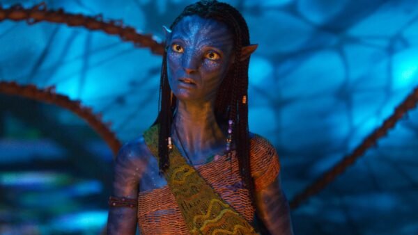 Un extraterrestre humanoïde à la peau bleue d'Avatar, aux cheveux tressés et aux accessoires perlés, se tient sur un fond bleu lumineux, vêtu d'une guêpe à motifs - un look emblématique du film oscarisé pour Meilleurs Effets Visuels.