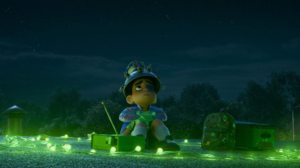 Un enfant animé portant un casque fait maison est assis sur un toit la nuit, entouré de guirlandes lumineuses vertes, avec une radio et un sac à dos à proximité - évoquant l'esprit fantaisiste d'Elio de Pixar au milieu des cimes des arbres.