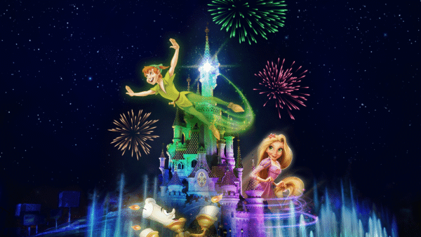 Les personnages animés de Disney, Peter Pan, Clochette, Raiponce et Lumière, apparaissent au-dessus du château de Disneyland Paris illuminé par des feux d'artifice et des fontaines la nuit.