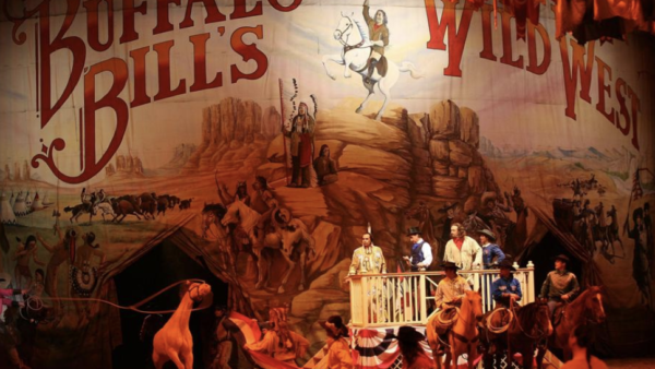 Des artistes en tenue western se tiennent sur scène devant une toile de fond "Buffalo Bill's Wild West Show", recréant des scènes de cow-boys et d'Amérindiens du dernier spectacle qui s'est tenu le 13 mars 2020.