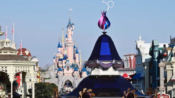 Vue de la rue principale de Disneyland Paris avec une grande décoration "30" marquant le 30e anniversaire du parc et le château de la Belle au bois dormant en arrière-plan, célébrant non seulement la magie mais aussi l'impact économique de Disneyland sur l'économie locale.