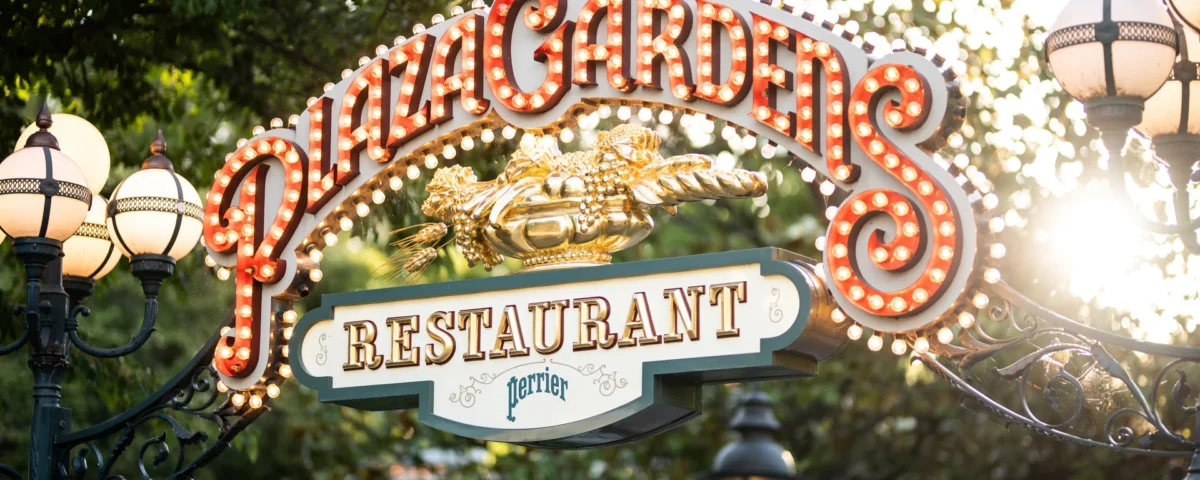 Le panneau d'entrée du restaurant Plaza Gardens, comportant des lettres lumineuses et entouré de lampadaires décoratifs et de verdure, annonce la rénovation du restaurant et indique qu'il sera fermé en 2027.