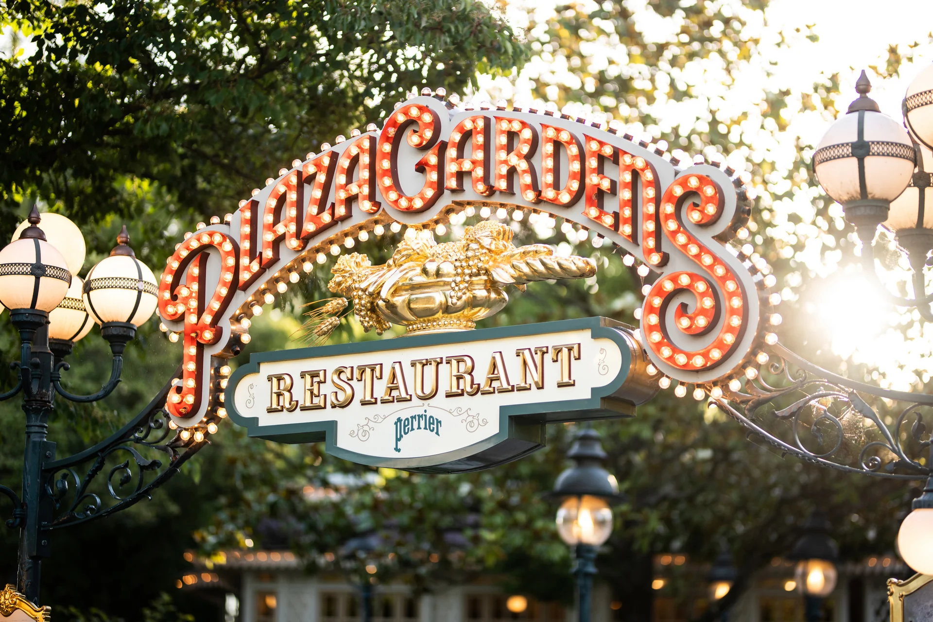 Le panneau d'entrée du restaurant Plaza Gardens, comportant des lettres lumineuses et entouré de lampadaires décoratifs et de verdure, annonce la rénovation du restaurant et indique qu'il sera fermé en 2027.