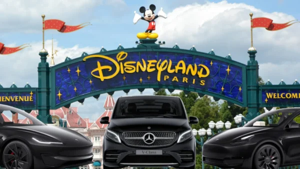 Entrée de Disneyland Paris avec une statue de Mickey Mouse au-dessus du panneau et trois voitures noires, dont un taxi Mercedes. Pour les personnes intéressées par le tarif taxi Disneyland, ces taxis offrent un transport pratique jusqu'à l'entrée du parc.