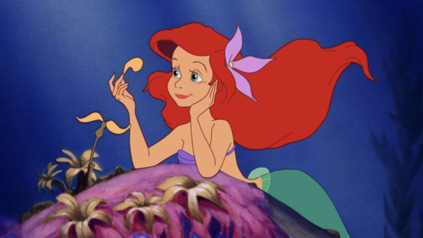 Sirène animée aux longs cheveux roux et à la queue verte reposant sur un rocher sous l'eau, tenant un objet jaune et ayant l'air pensif - une scène inspirée de La Petite Sirène, dont la sortie a eu lieu le 17 novembre 1989.