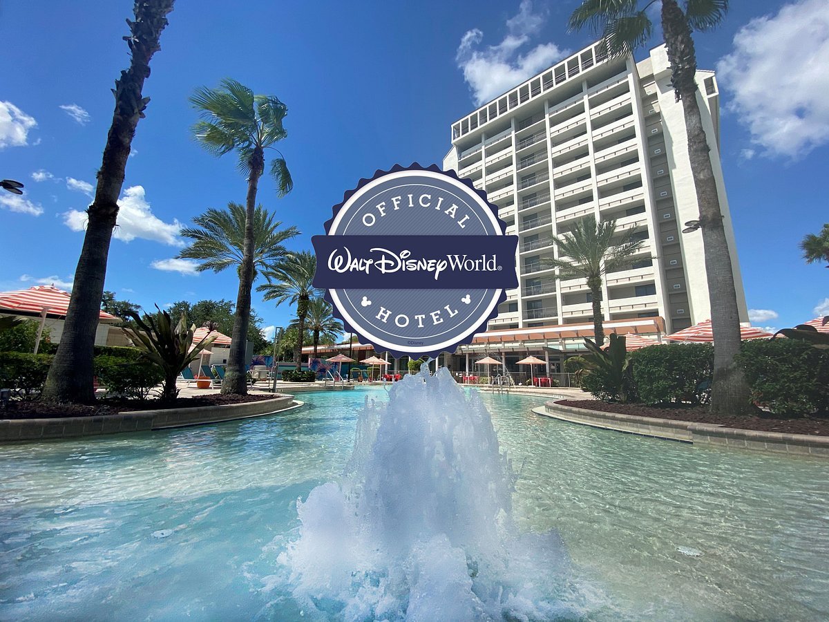 Un bâtiment hôtelier au bord d'une piscine avec une fontaine, des palmiers et un grand badge "Official Walt Disney World Hotel" au centre - un endroit idéal pour séjourner pendant votre aventure à Walt Disney World.
