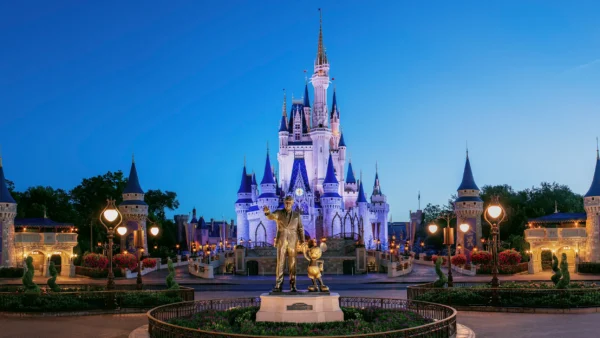 La statue en bronze de Walt Disney et Mickey Mouse se dresse devant le château de Cendrillon au crépuscule à Walt Disney World, où les secrets et les moments magiques semblent presque insaisissables.