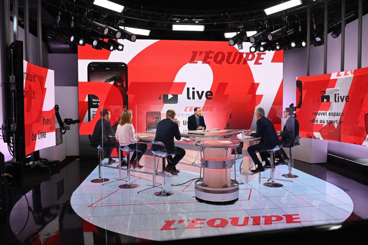 Un groupe de six personnes est assis autour d'une table circulaire dans un studio de télévision très éclairé portant la marque "L'ÉQUIPE", discutant des derniers événements sportifs en France, diffusés en direct sur la célèbre chaîne de sport.