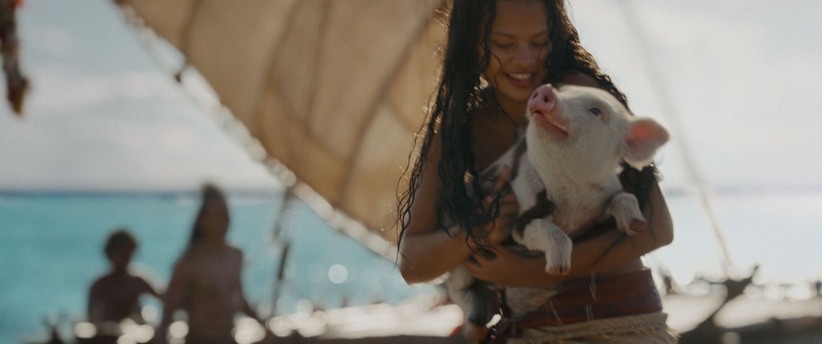 Une jeune femme aux longs cheveux mouillés, qui rappelle Vaiana, sourit en tenant un petit cochon près de l'océan, avec un voilier et deux personnes en arrière-plan — une scène digne d'une héroïne Disney de La Légende du bout du monde.