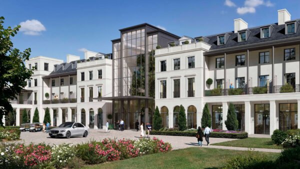 Un hôtel 5 étoiles moderne de plusieurs étages, doté d'une grande entrée vitrée, entouré de verdure, avec des passants et des voitures garées devant, sous un ciel bleu limpide — à quelques minutes seulement de Disneyland Paris.