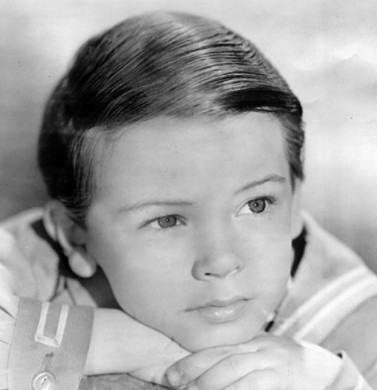 Portrait d'un jeune garçon, qui rappelle Bobby Driscoll, aux cheveux soigneusement peignés, vêtu d'une chemise à col, le menton posé sur ses mains et le regard légèrement tourné vers le côté — une image qui capture tout le charme d'un enfant du 3 mars 1937.