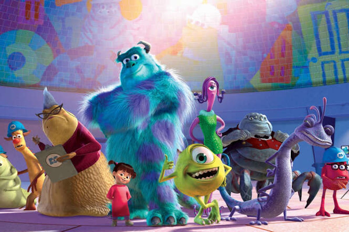 Un groupe de monstres animés et un enfant se tiennent ensemble dans une pièce colorée, avec diverses formes et motifs sur le mur derrière eux, illustrant l'univers fantaisiste de « Monstres et Cie » tel qu'il apparaissait lors de sa sortie le 2 novembre 2001.