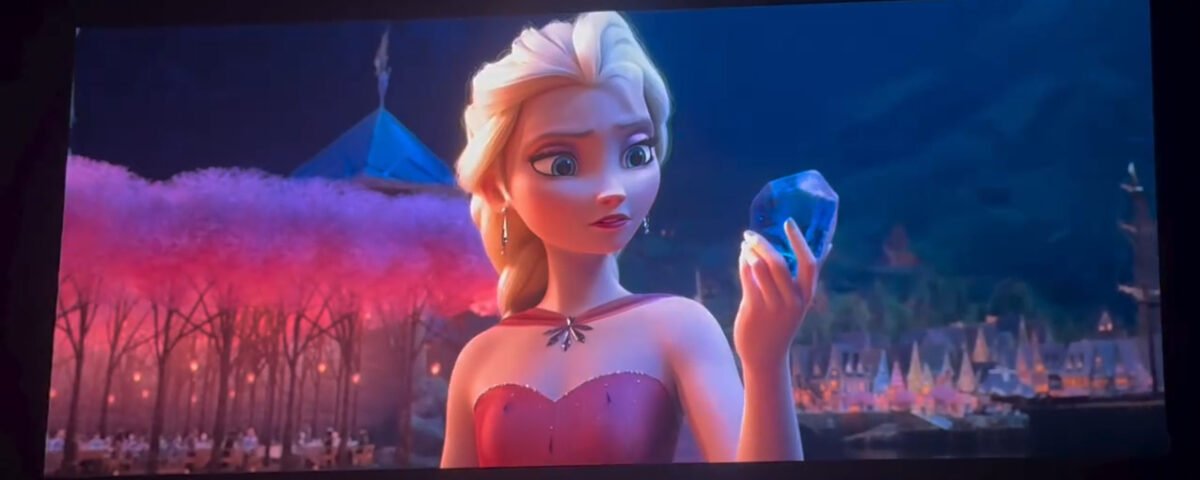 Un personnage d'animation aux cheveux blonds, vêtu d'une robe rouge, tient un grand cristal bleu, avec en arrière-plan des arbres roses et un paysage urbain nocturne — une scène qui rappelle les moments magiques de Disney dévoilés lors du D23 et qui inspirent de futurs projets.
