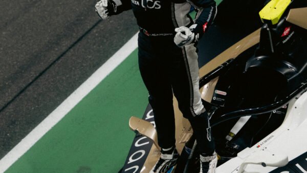 Un pilote de course, en tenue complète, se tient debout sur le toit d'une Jaguar de Formule E sur un circuit, levant les poings en signe de victoire, alors que l'engouement pour les courses de Formule E — désormais disponibles en streaming sur Disney+ via un diffuseur mondial — atteint de nouveaux sommets.