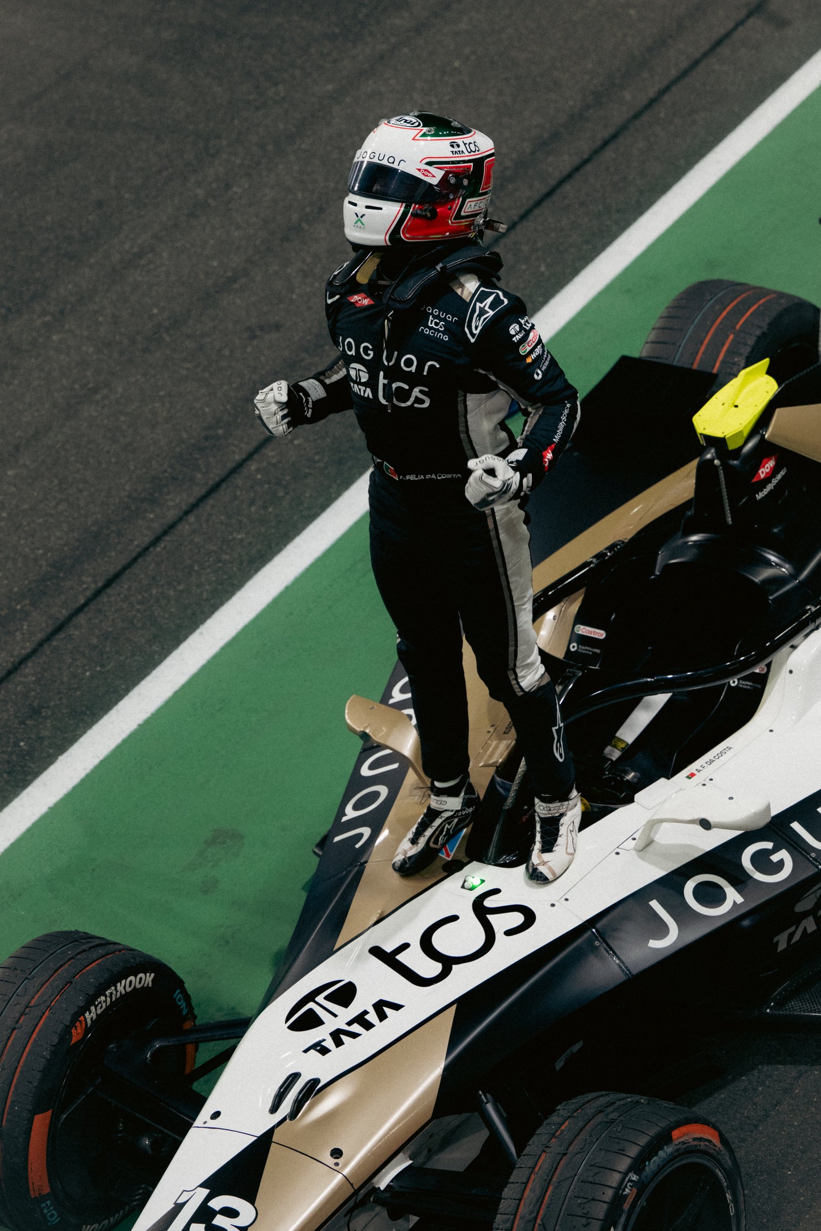 Un pilote de course, en tenue complète, se tient debout sur le toit d'une Jaguar de Formule E sur un circuit, levant les poings en signe de victoire, alors que l'engouement pour les courses de Formule E — désormais disponibles en streaming sur Disney+ via un diffuseur mondial — atteint de nouveaux sommets.