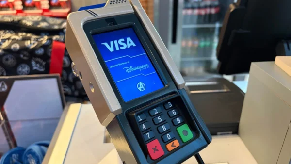 Gros plan sur un terminal de paiement par carte affichant un écran Visa avec le logo de Disneyland Paris dans un magasin, mettant en avant la technologie moderne des terminaux de paiement.