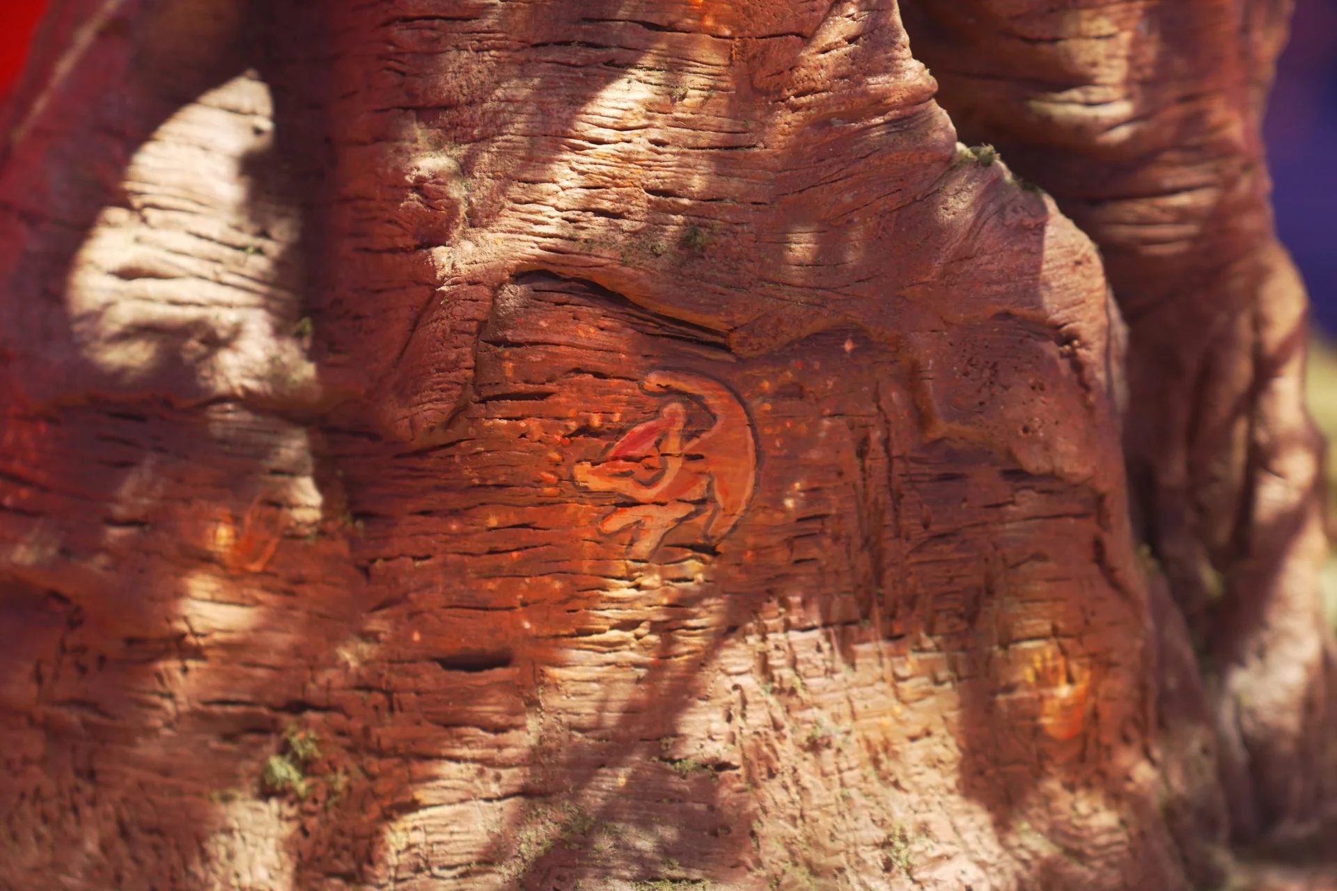 Gros plan sur un tronc d'arbre où est gravé, dans l'écorce, un animal stylisé, peut-être inspiré du Roi Lion, mis en valeur par les jeux de lumière et d'ombres. Ce motif complexe évoque un « monde immersif », invitant les spectateurs à imaginer des maquettes détaillées qui donnent vie à cette scène enchanteresse.