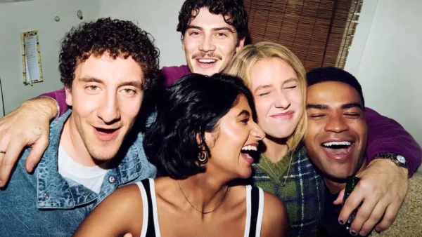 Cinq jeunes adultes sourient et rient ensemble, serrés les uns contre les autres, en posant pour une photo prise en intérieur, qui rappelle une photo de groupe tirée d’une série télévisée populaire comme la « saison 2 » de la série acclamée « Adults » diffusée sur FX.